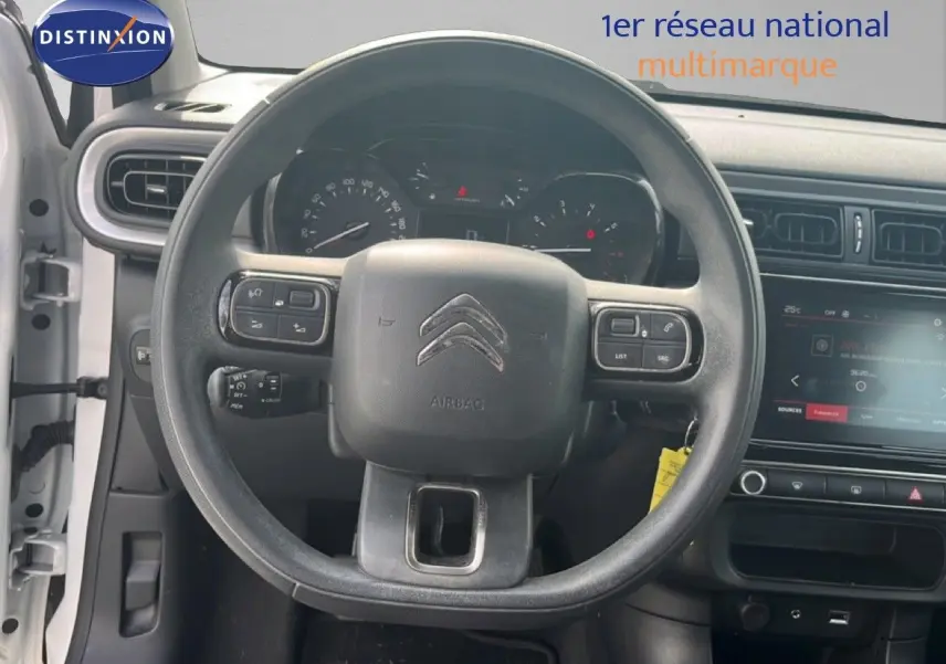 Vue intérieure centrée sur le volant noir d'une Citroën C3 blanche de 2018 avec tableau de bord et écran tactile visibles.