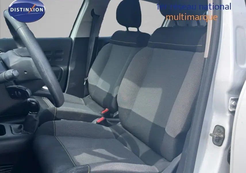 Vue intérieure côté conducteur de la Citroën C3 blanche 2018, montrant les sièges en tissu gris et la boîte manuelle.