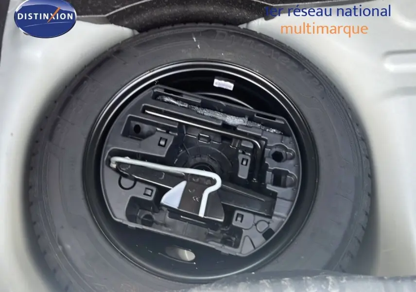Roue de secours noire avec outillage intégré, vue en plongée dans le coffre d'une Citroën C3 blanche 2018.