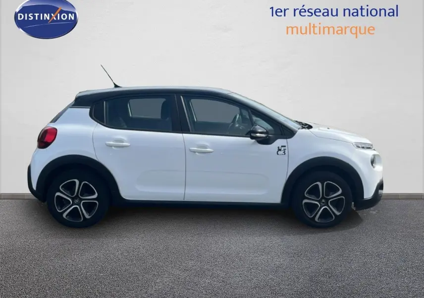 Profil droit d'une Citroën C3 blanche 2018 avec toit noir et jantes distinctives, sur fond neutre intérieur.