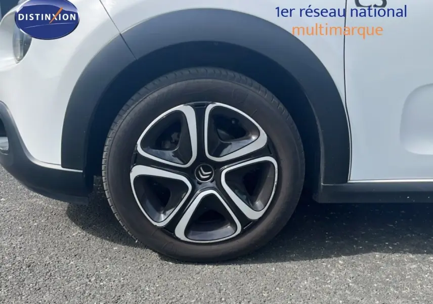 Gros plan sur la roue avant gauche d'une Citroën C3 blanche de 2018 avec jante noire et argentée au design distinctif.