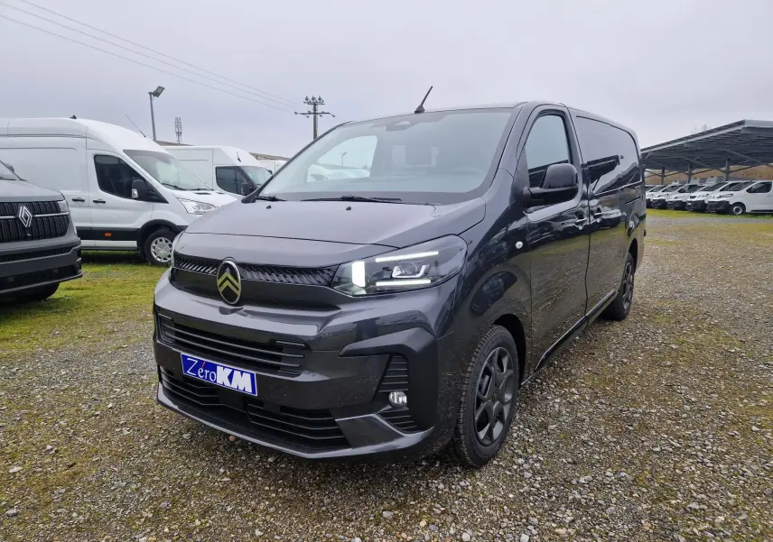 Vue 3/4 avant droit d'un Citroën Jumpy Cabine Approfondie gris titane avec feux LED allumés sur un parking extérieur.