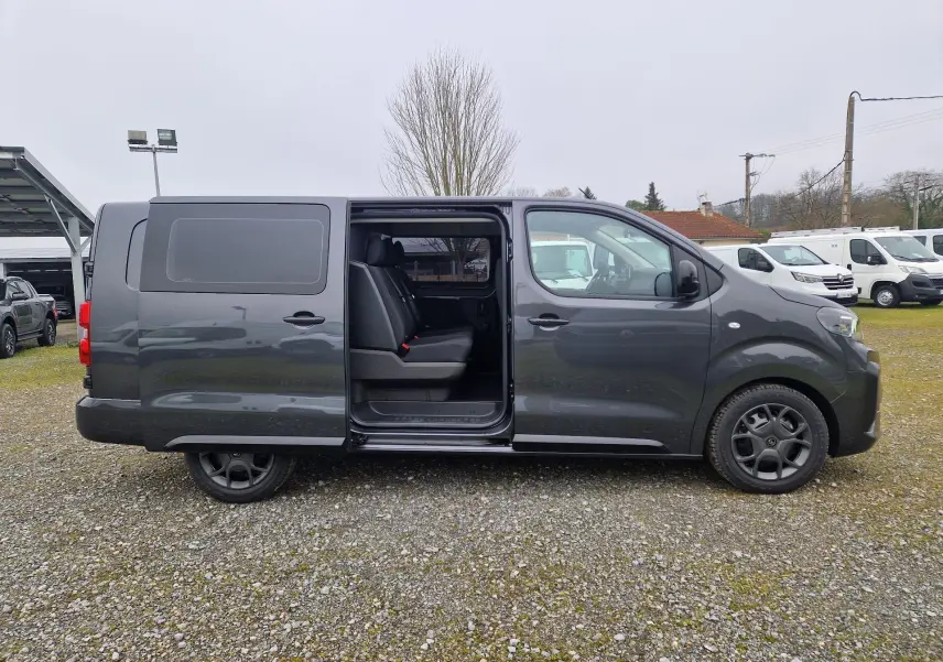 Vue de profil côté droit d'un Citroën Jumpy Cabine Approfondie gris titane avec porte coulissante ouverte révélant les sièges arrière.
