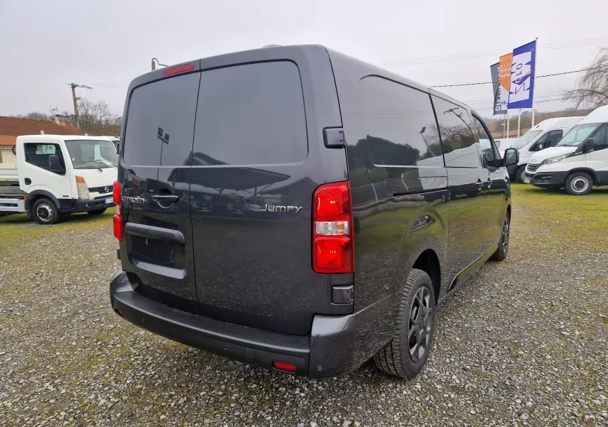 Vue 3/4 arrière droite d'un Citroën Jumpy cabine approfondie gris titane avec vitres arrière teintées et feux rouges visibles.