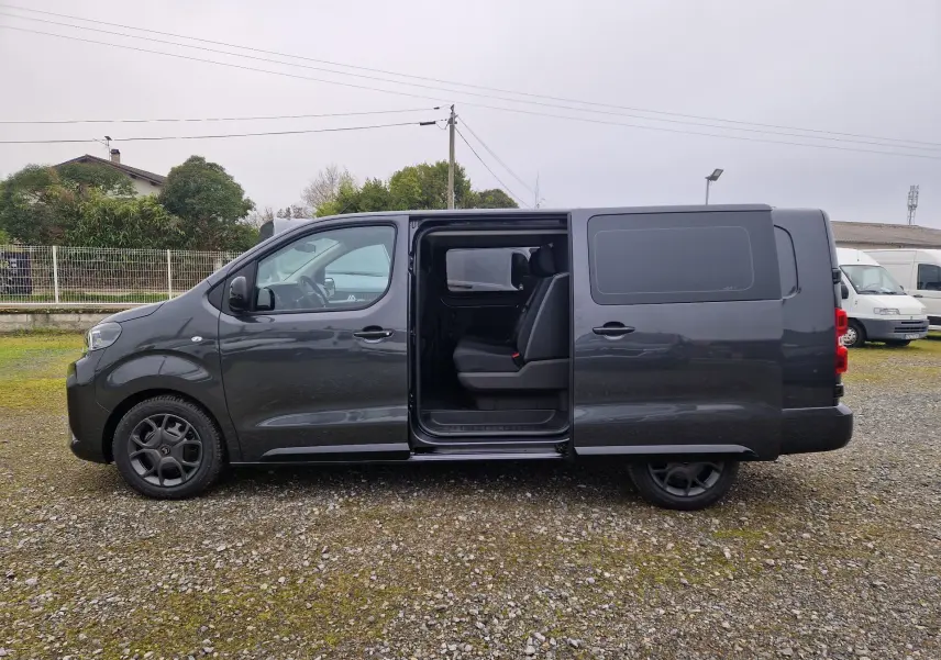 Vue de profil côté gauche d'un Citroën Jumpy Cabine Approfondie gris titane avec porte coulissante ouverte montrant l'intérieur 5 places.