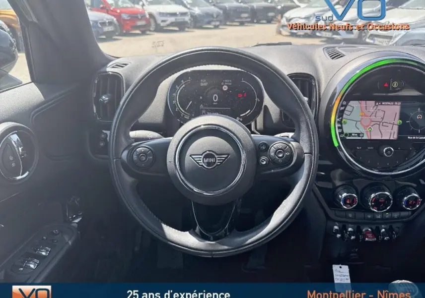 Vue intérieure centrée sur le volant sport MINI avec tableau de bord numérique et écran tactile de navigation allumé.
