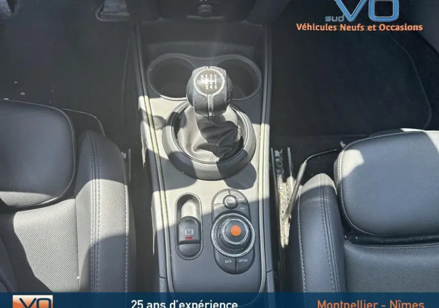 Vue plongeante sur la console centrale de la MINI Countryman gris clair, mettant en valeur le levier de vitesses manuel et l'accoudoir central cuir noir.