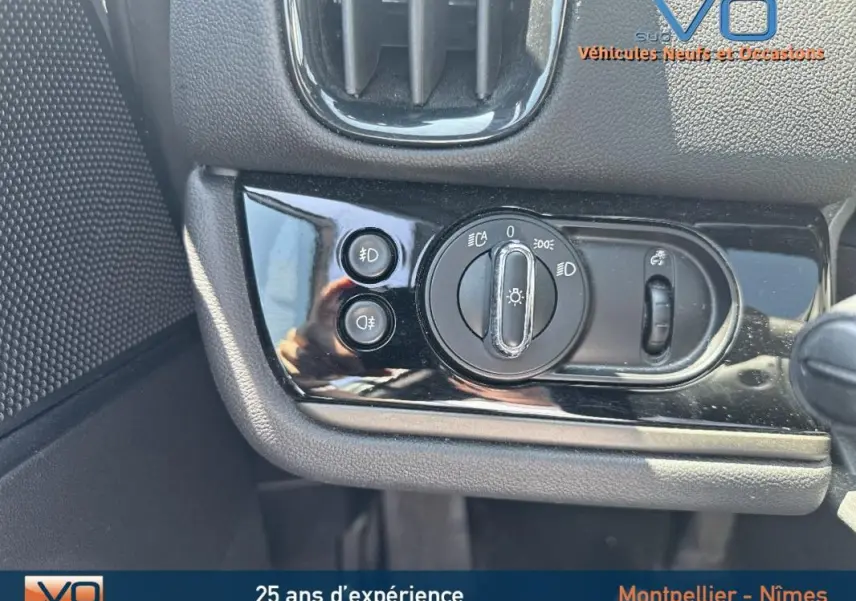 Gros plan sur le panneau de commande des phares et antibrouillard dans l'habitacle d'une MINI Countryman gris clair.