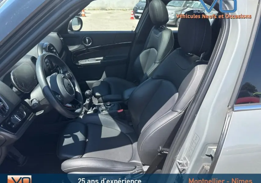 Intérieur côté conducteur d'une MINI Countryman gris clair 2021 avec sièges cuir noirs et volant sport.