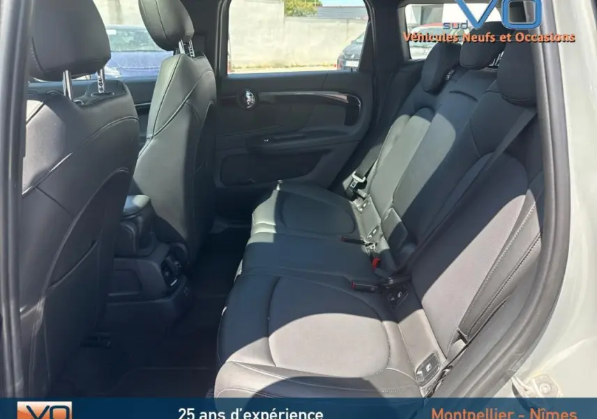 Vue latérale droite de l'habitacle arrière d'un MINI Countryman gris clair, sièges en cuir noir et accoudoir central.