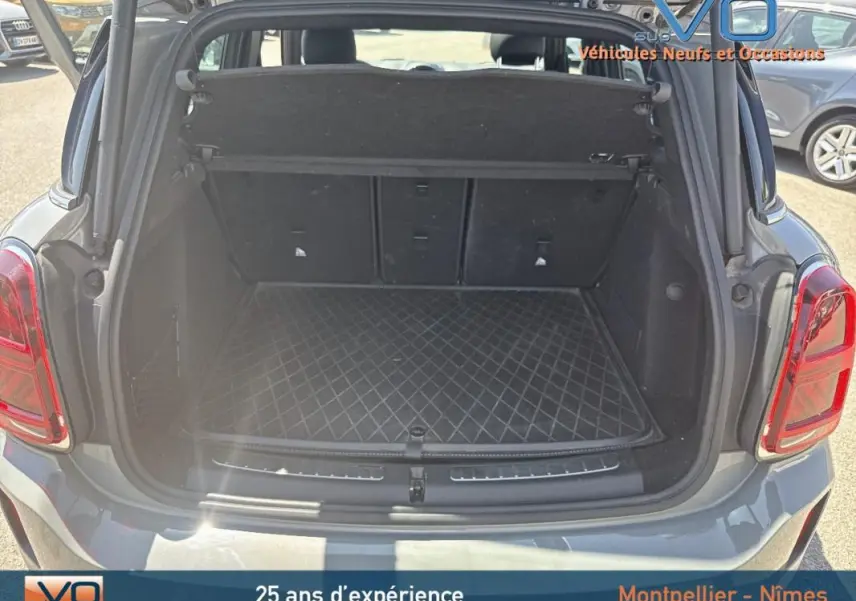 Coffre ouvert d'une MINI Countryman gris clair 2021, vue arrière montrant l'espace de chargement et tapis matelassé.