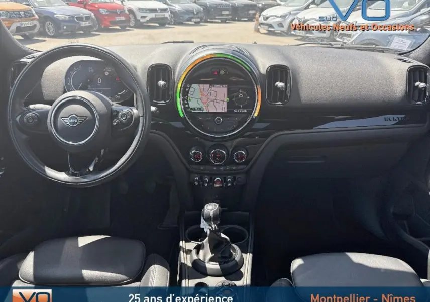 Vue intérieure avant du tableau de bord d'une MINI Countryman gris clair avec écran tactile central et volant sport.