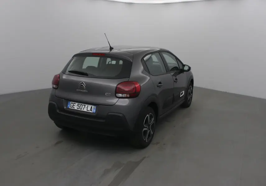 Citroën C3 gris platinium vue 3/4 arrière droit, avec feux arrière arrondis et jantes spécifiques.