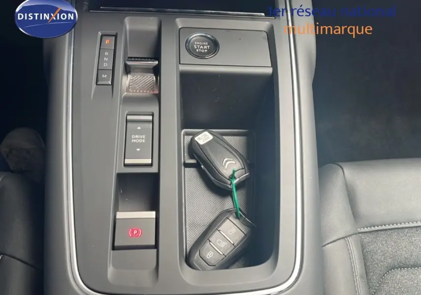 Vue plongeante sur la console centrale noire du Citroën C5 Aircross 2025 avec clés, bouton start et commandes de boîte auto.