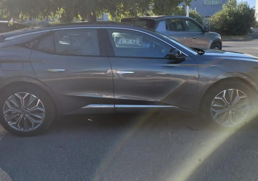 Vue de profil côté gauche d'une DS4 hybride gris métallisé 2024, soulignant ses lignes dynamiques et ses jantes distinctives.