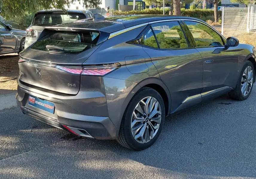 Vue 3/4 arrière droite d'une DS4 hybride gris métallisé 2024 avec feux arrière distinctifs et jantes stylisées.