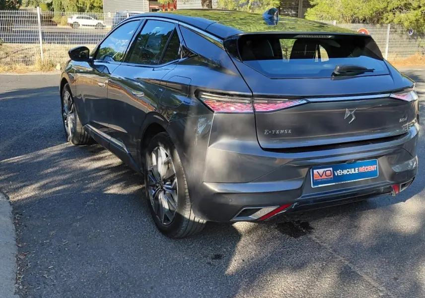 Vue 3/4 arrière droite d'une DS4 gris métallisé 2024, version Hybride E-Tense avec feux arrière effilés et logo DS distinctif.