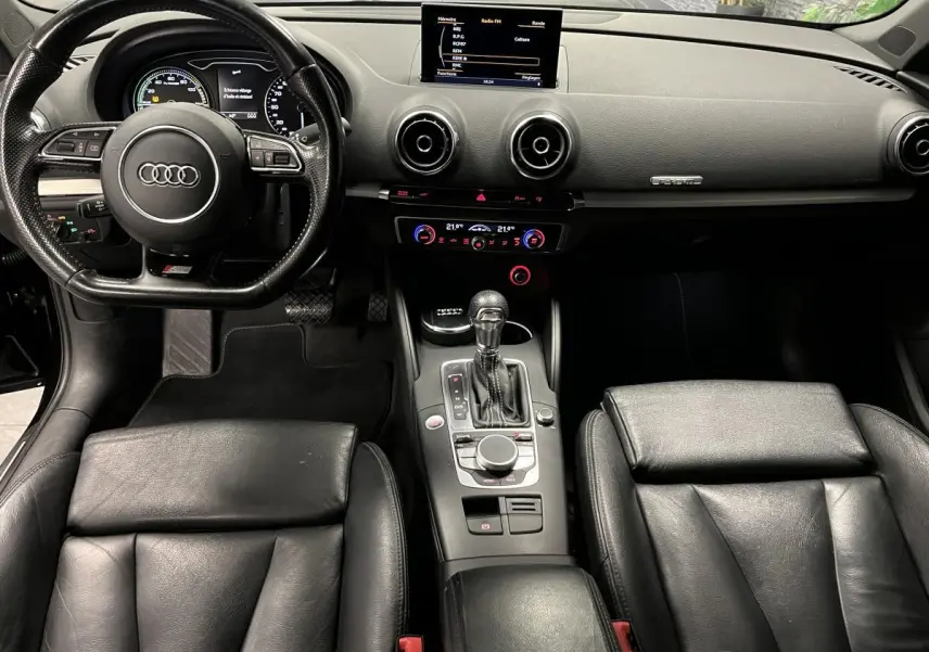 Intérieur noir cuir de l'Audi A3 1.4 TFSI e-tron S line 2015, vue centrale sur tableau de bord et volant sport.