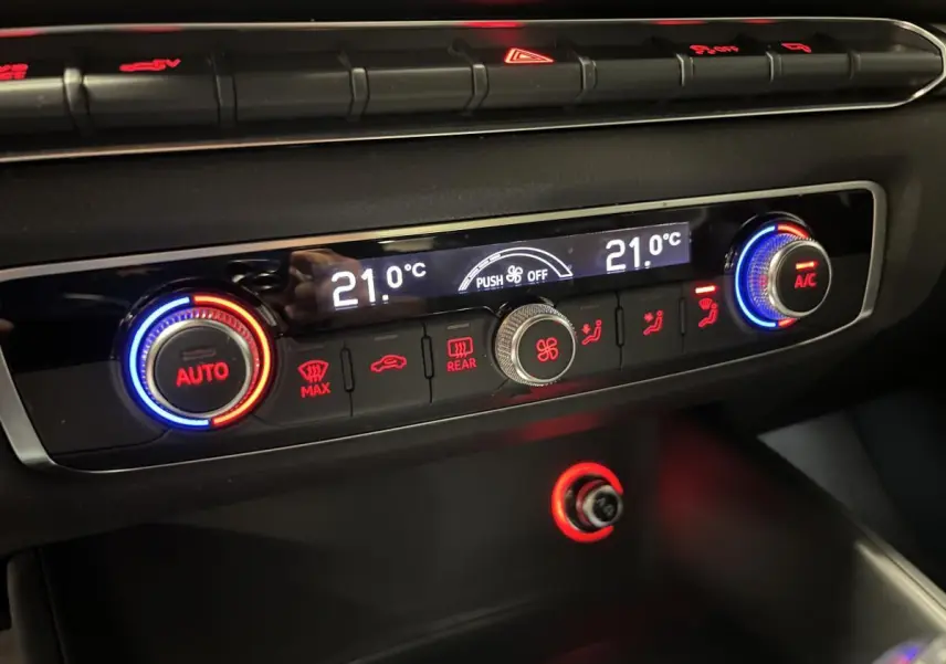 Détail de la console de climatisation automatique de l'Audi A3 1.4 TFSI e-tron S line 2015 avec affichage digital et boutons rétroéclairés rouge et bleu.