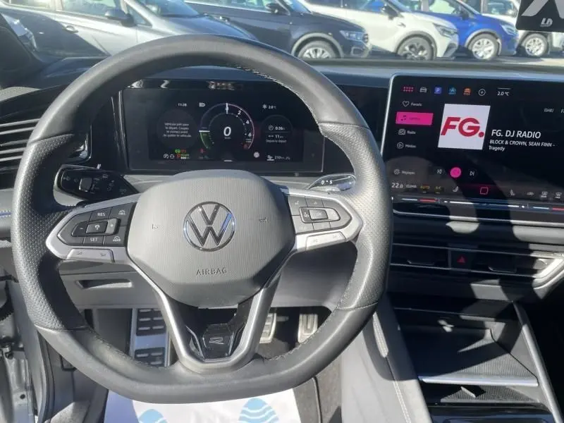 Vue intérieure centrée sur le volant noir du Volkswagen Tiguan 1.5 eHybrid 2025 avec tableau de bord numérique et écran tactile.
