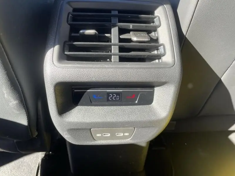 Vue rapprochée de la console arrière du Volkswagen Tiguan 1.5 eHybrid gris métal, avec réglage de climatisation à 22°C et ports USB.