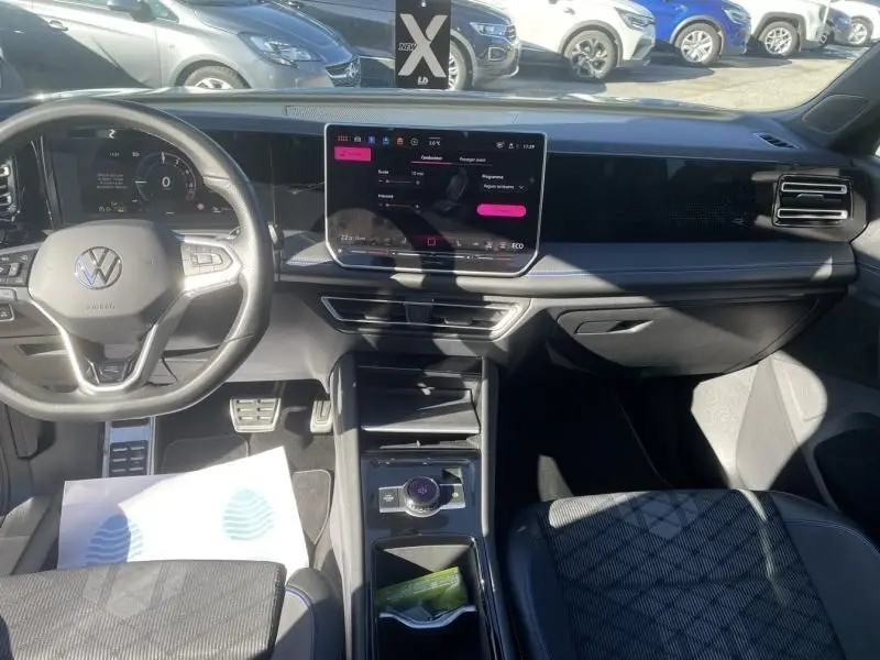 Vue intérieure du tableau de bord et volant du Volkswagen Tiguan 1.5 eHybrid gris métal, avec écran tactile central et finitions R-line.