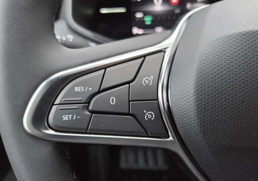 Gros plan sur les commandes de régulateur de vitesse au volant d’une Renault Clio V gris schiste métal.