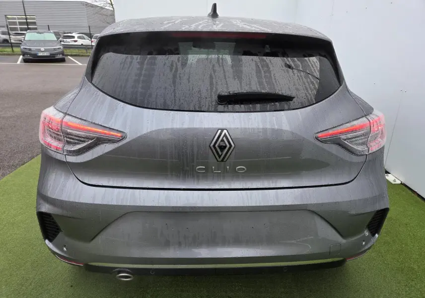 Vue arrière d'une Renault Clio gris schiste métal 2025 avec feux LED en forme de C et lunette arrière surteintée.