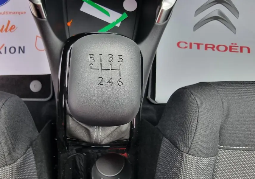 Vue rapprochée du levier de vitesses manuel gris du Citroën C3 Aircross 2022, avec sièges tissu noirs autour.