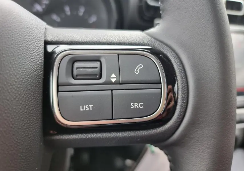 Gros plan sur les commandes multimédia au volant du Citroën C3 Aircross 2022, finition C-Series, intérieur noir.