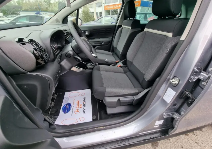 Vue intérieure côté conducteur de la Citroën C3 Aircross gris Artence, sièges tissu noir et tableau de bord moderne.
