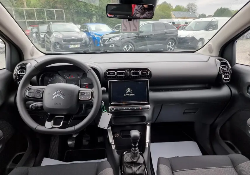 Vue intérieure avant du Citroën C3 Aircross 2022, tableau de bord noir avec écran tactile central et volant multifonction.