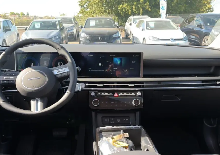 Vue intérieure frontale du tableau de bord et volant cuir noir du Hyundai Tucson 2026, avec écran tactile large et commandes au volant.