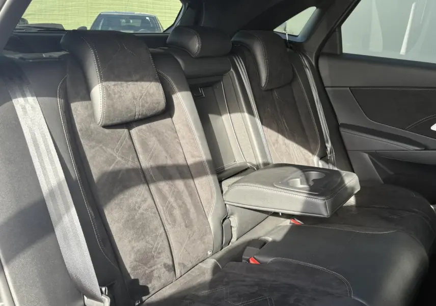 Vue intérieure arrière du DS7 2024 en Alcantara noir profond avec accoudoir central déployé et surpiqûres Carmin et Or.