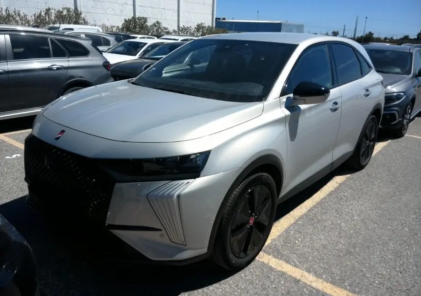 DS7 1.6 E-Tense 2024 en cristal pearl, vue 3/4 avant droit avec jantes noires et calandre marquée noire.