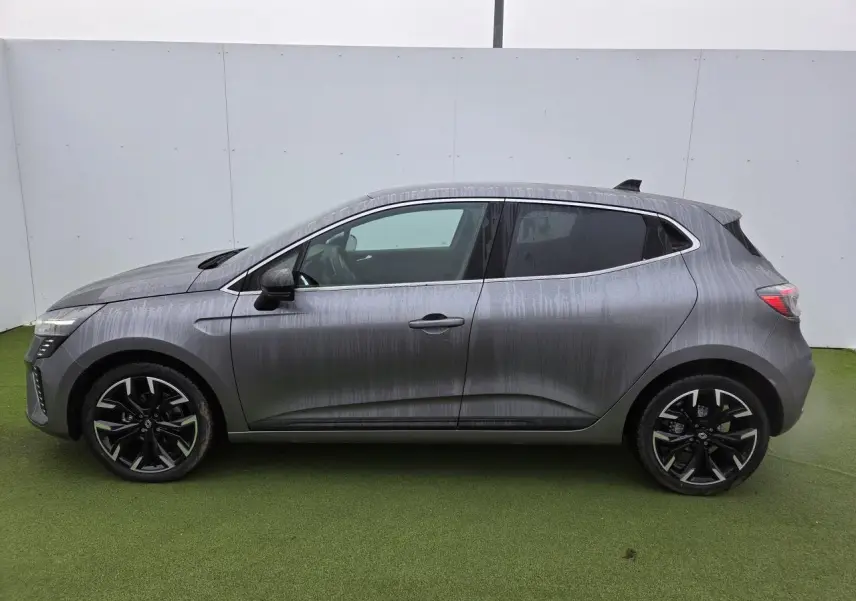 Profil droit d'une Renault Clio 2025 gris schiste métal avec jantes alliage noires et contours de vitres chromés.
