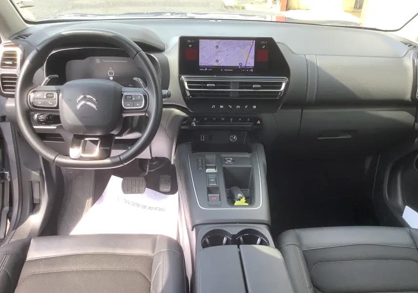 Vue intérieure avant du Citroën C5 Aircross Hybrid 136 e-DCS6 Max, tableau de bord noir avec écran tactile et volant multifonction.