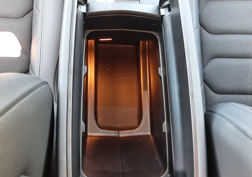 Vue plongeante sur le rangement central éclairé entre les sièges gris noir du Citroën C5 Aircross Hybrid 2024.