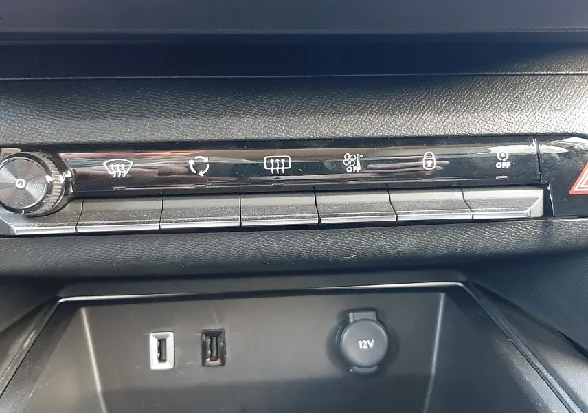 Vue rapprochée de la console centrale noire du Citroën C5 Aircross Hybrid 136 e-DCS6 Max, avec boutons de contrôle et prises USB et 12V.