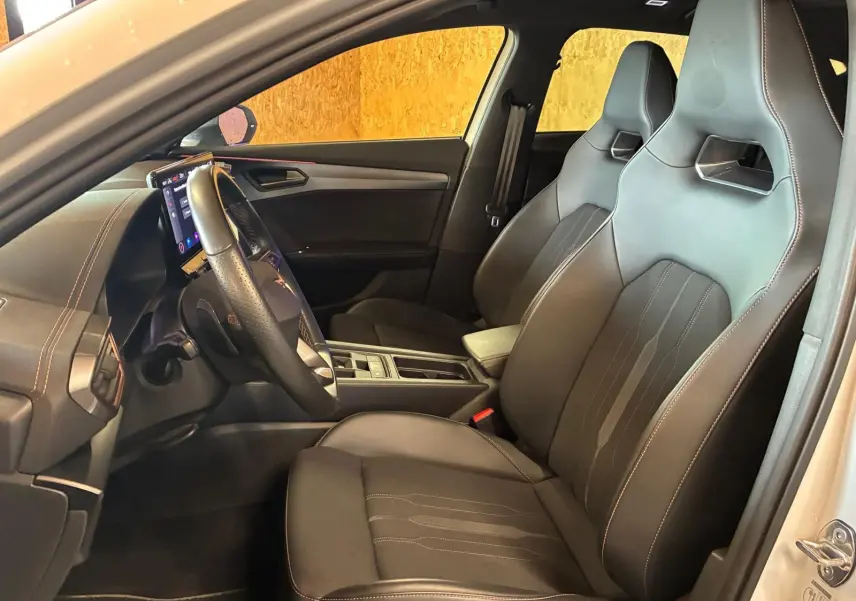 Vue intérieure côté conducteur de la CUPRA Formentor gris 2024, sièges sport en tissu noir avec surpiqûres contrastées.