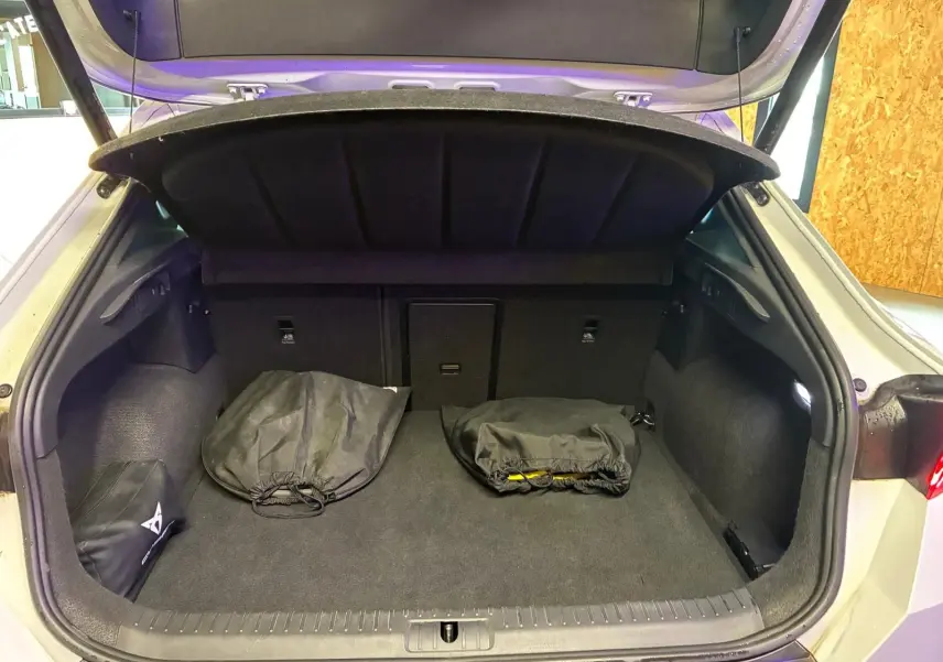 Coffre ouvert d’une CUPRA Formentor gris 2024, vue arrière, montrant un espace de chargement avec deux sacs noirs.