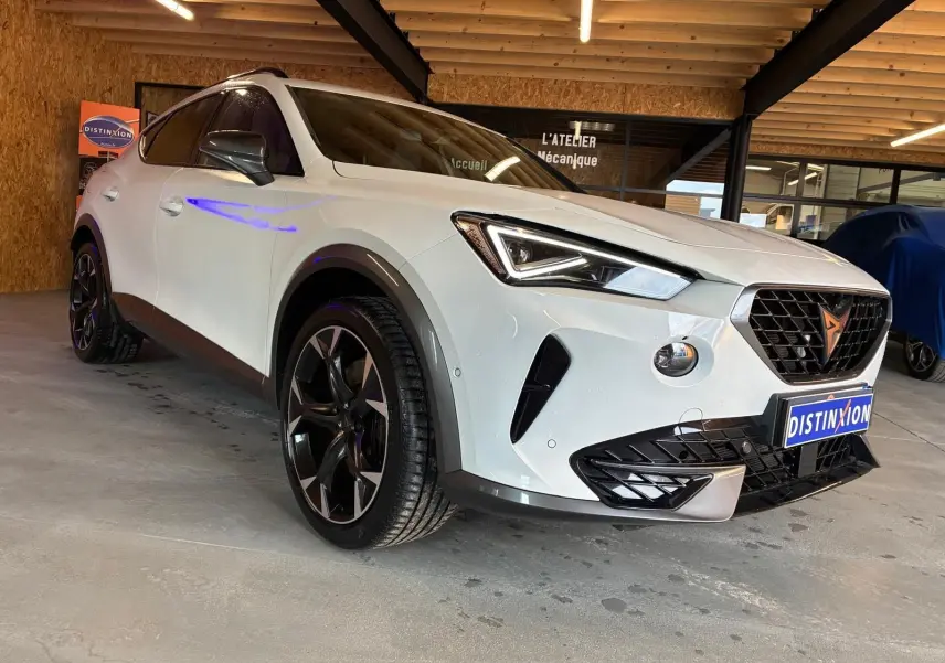 Vue 3/4 avant d'une CUPRA Formentor gris clair 2024, avec calandre noire et jantes noires distinctives.