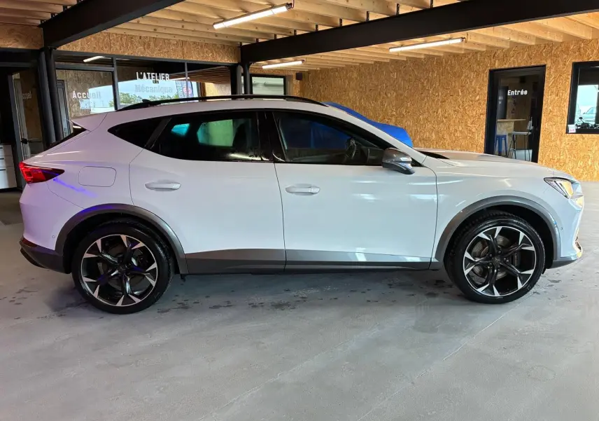 Vue de profil côté gauche du CUPRA Formentor gris 2024 avec jantes noires et toit noir dans un garage.