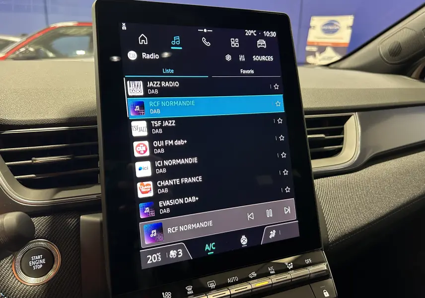 Écran tactile central vertical du Renault Captur blanc nacré, affichant les stations radio DAB dans l’habitacle.