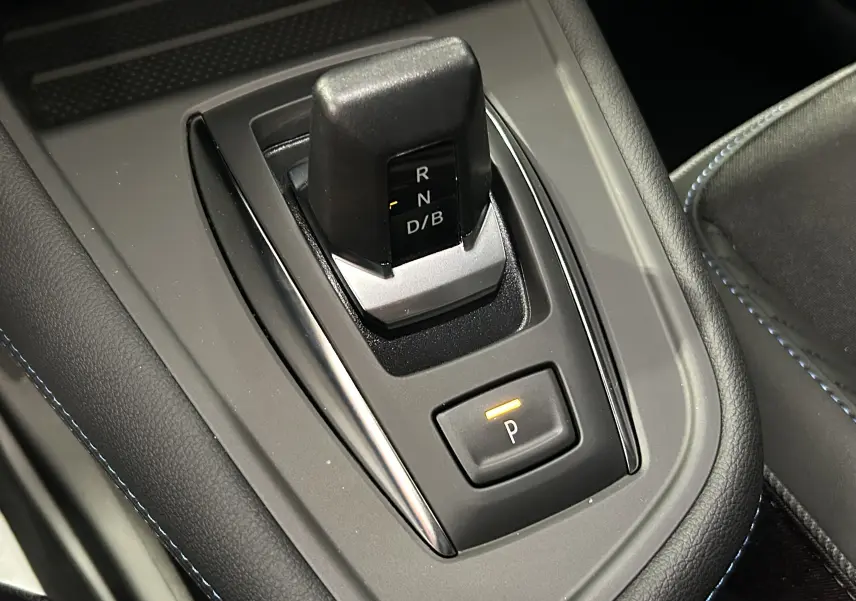 Gros plan sur la commande de boîte automatique noire du Renault Captur blanc nacré, avec bouton de parking éclairé.