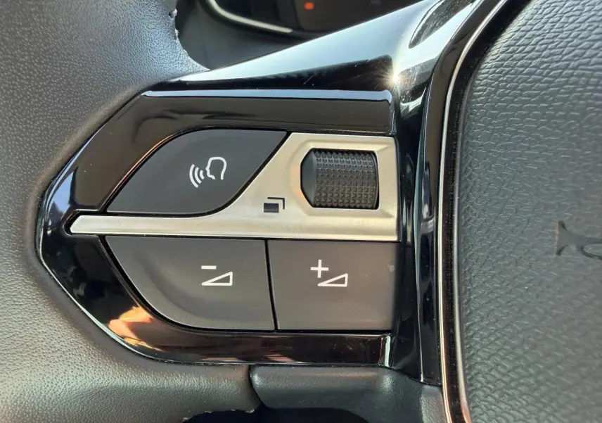 Gros plan sur les commandes audio et téléphone au volant d'une Peugeot 208 1.2 100ch gris Artense, côté gauche.