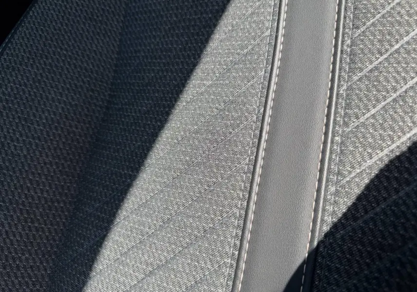 Détail du tissu gris Casual Lomsa avec surpiqûres contrastées sur l'accoudoir central avant du Peugeot 208 2025.