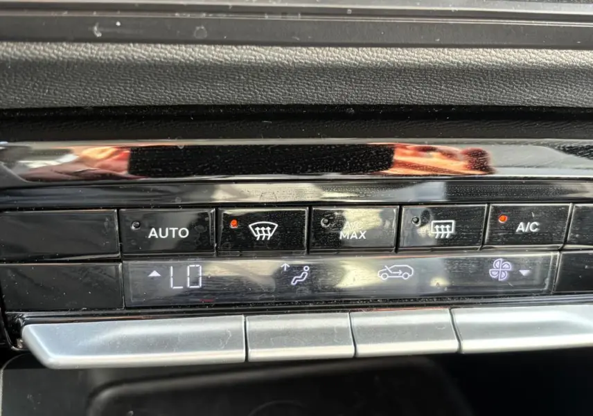 Gros plan sur la console de climatisation automatique de la Citroën C3 Turbo 100 ch, avec affichage digital et boutons noirs brillants.