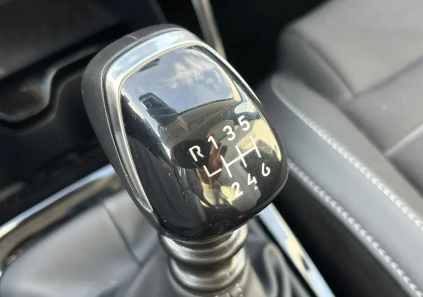 Gros plan sur le levier de vitesse manuel noir de la Citroën C3 Turbo 100 ch, avec coutures grises visibles sur les sièges.