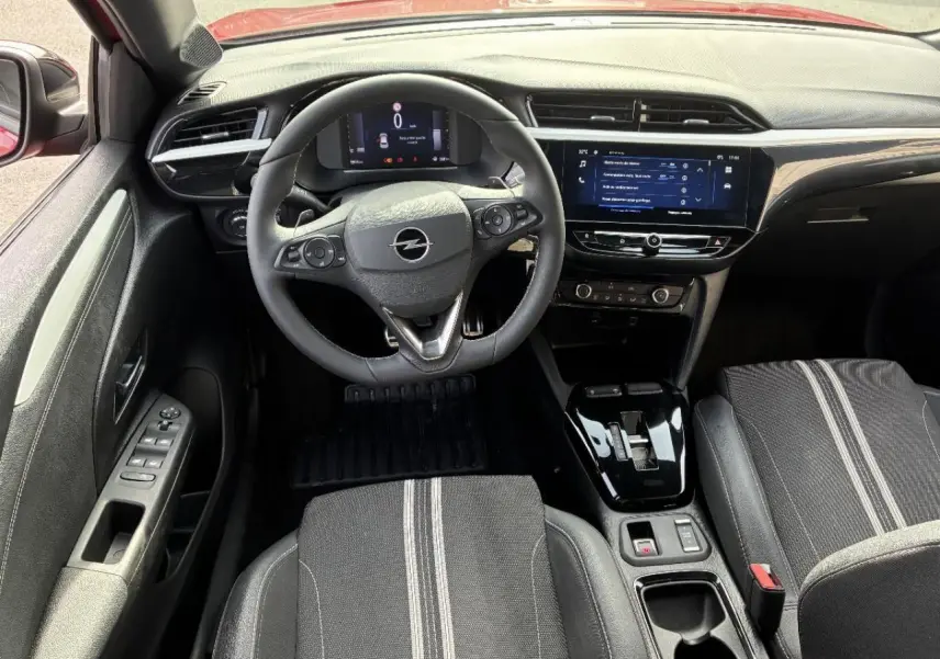 Vue intérieure avant de l’Opel Corsa 2025, volant multifonction, tableau de bord numérique et sellerie noire avec bandes grises.